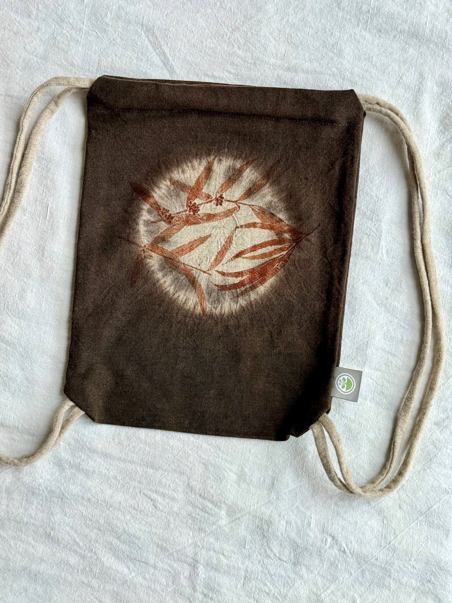 Brown drawstring bag with a circular shibori design eco-printed and naturally dyed by DOT 'N' POT