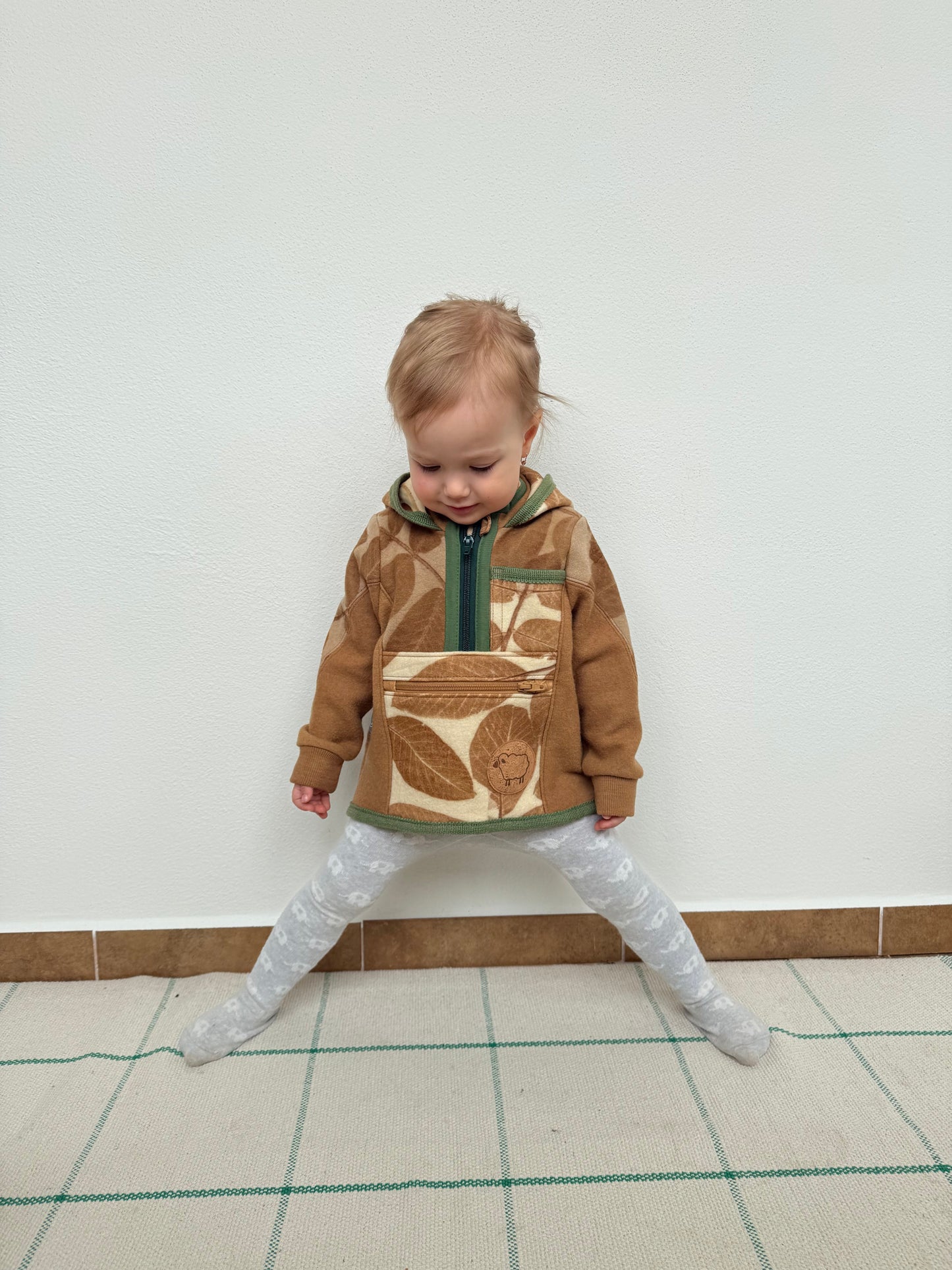 Child wearing a brown sweater with leaf pattern eco-printed and naturally dyed with walnut by DOT 'N' POT
