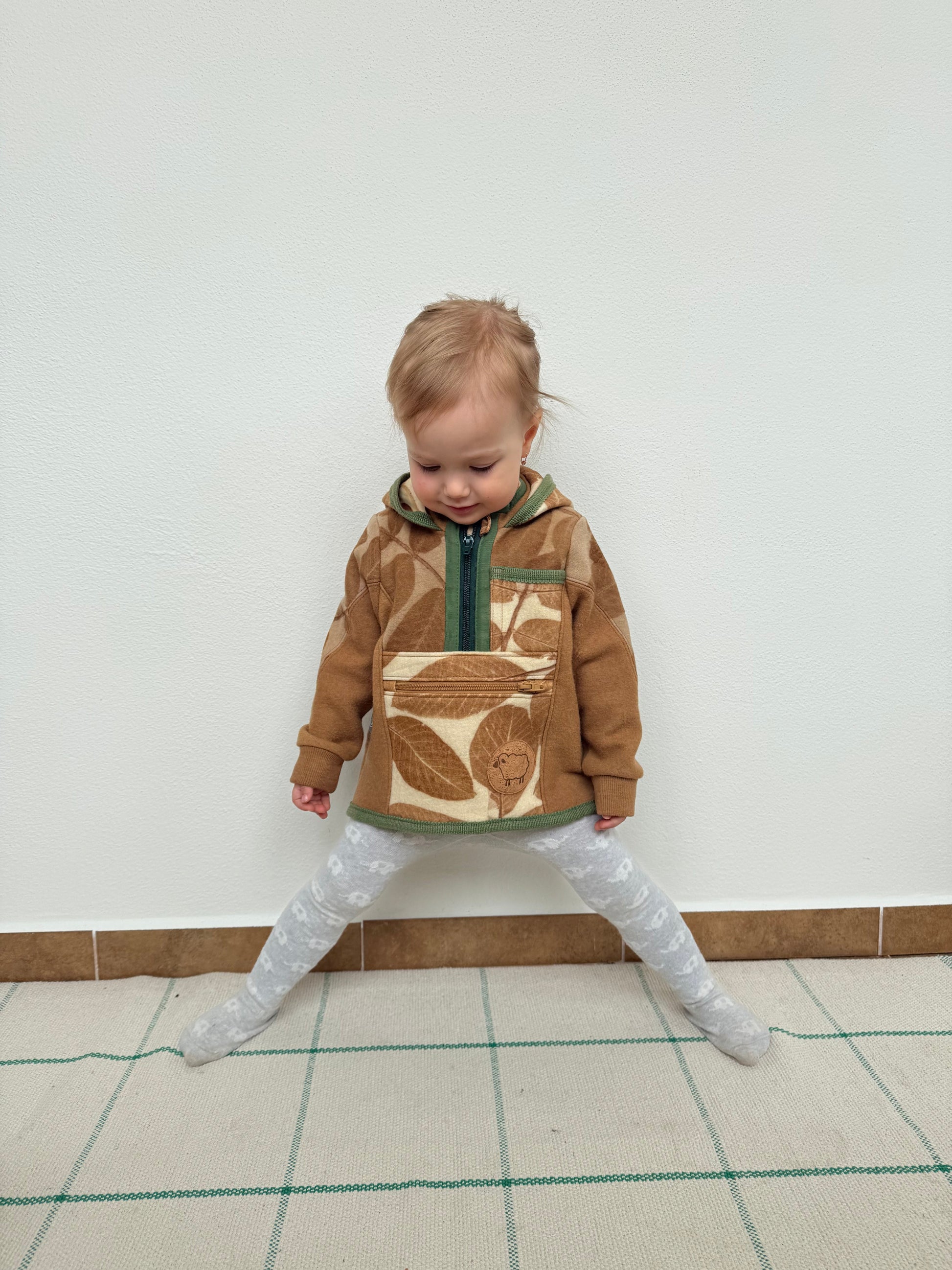 Child wearing a brown sweater with leaf pattern eco-printed and naturally dyed with walnut by DOT 'N' POT