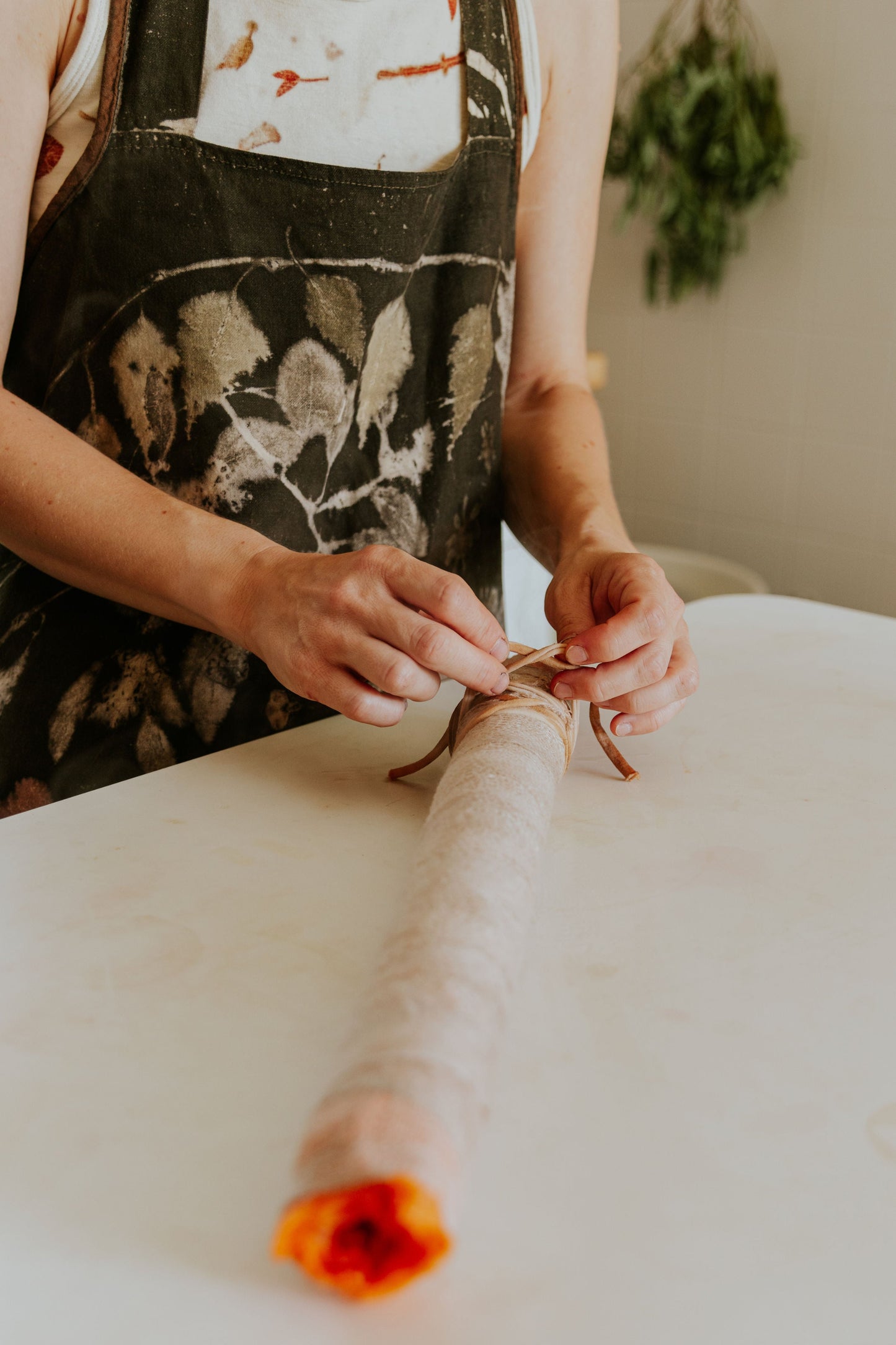 Ildikó in an eco-printed floral apron tying a bundle for dteaming in her DOT 'N' POT studio