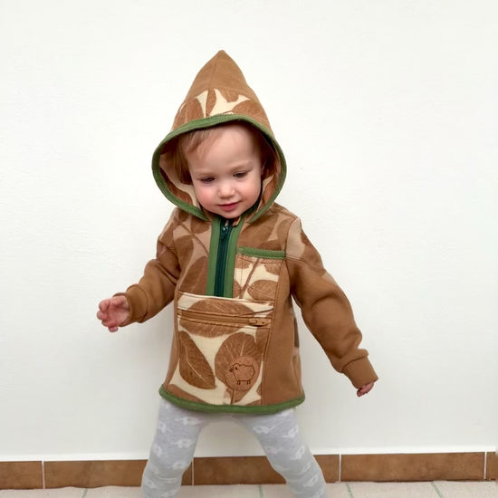 kid wearing a walnut dyed hooded merino wool sweater dancing against a white wall by DOT 'N' POT