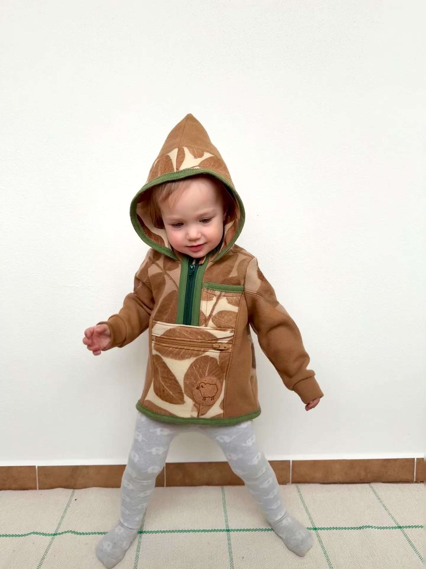 kid wearing a walnut dyed hooded merino wool sweater dancing against a white wall by DOT 'N' POT