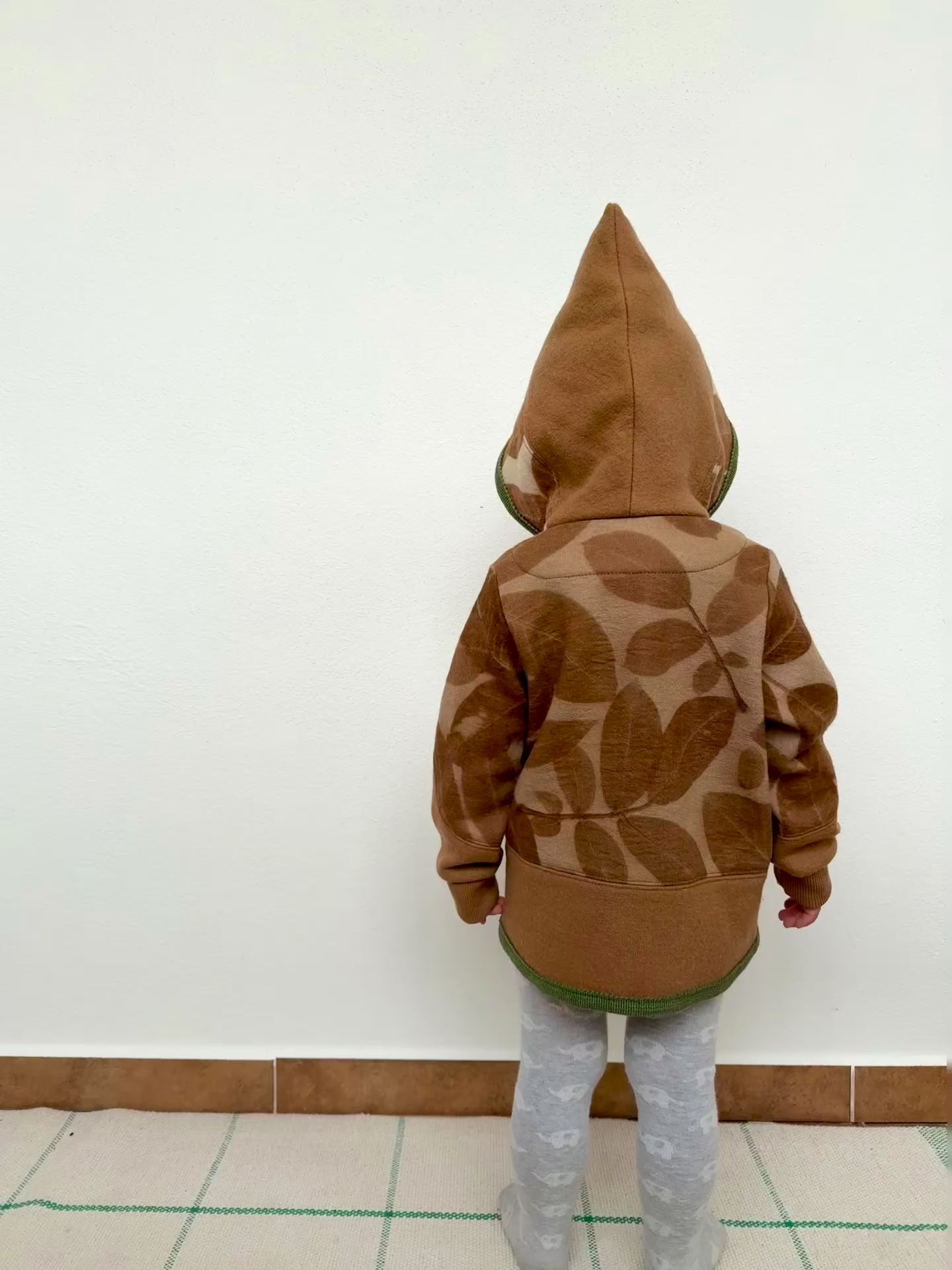 child wearing a merino wool hoodie that was dyed with walnut husks and eco-printed with walnut leaves